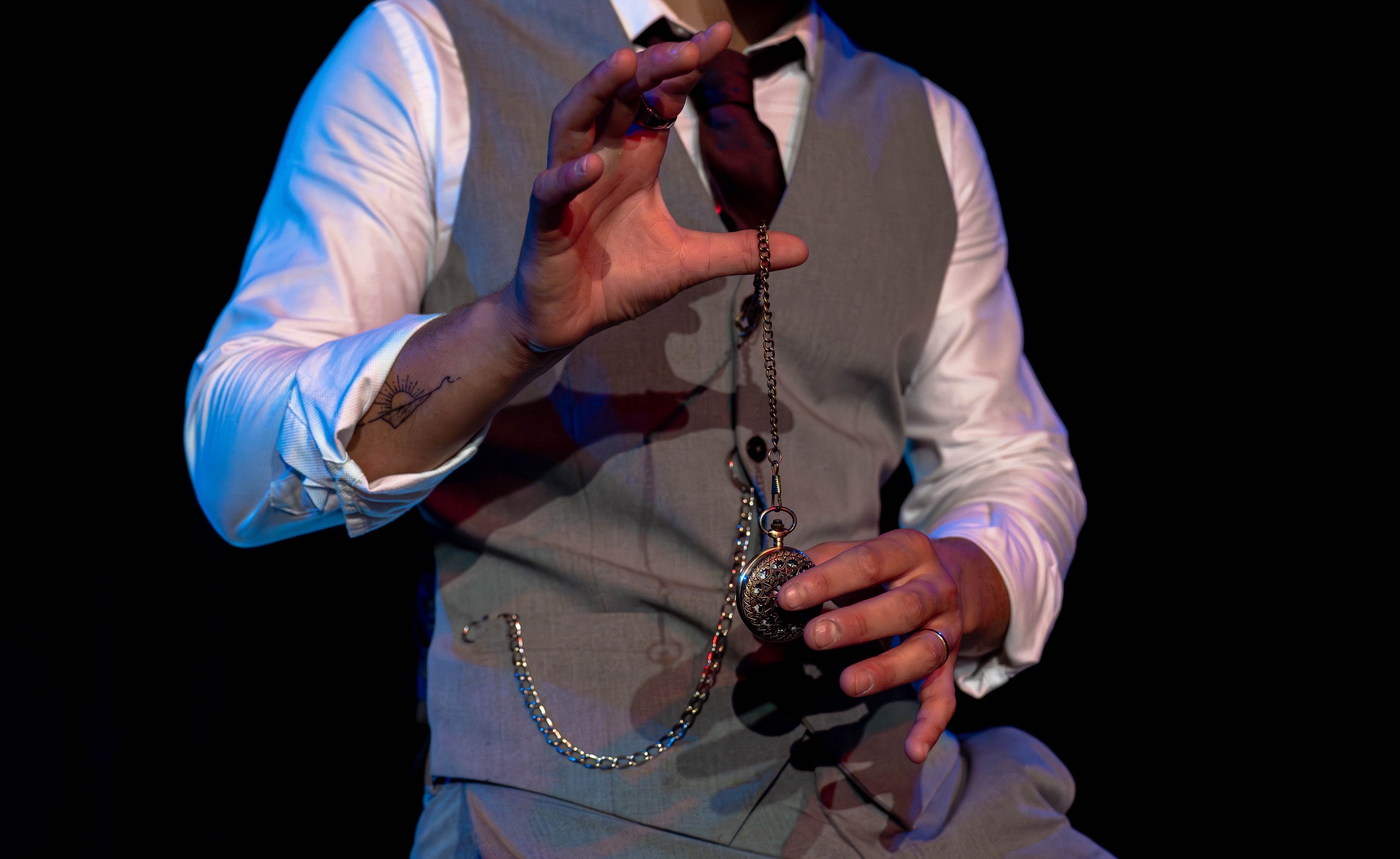 A pocket watch on a chain suspended from David Maestro's hand.